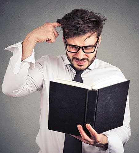 A confused student scratching his head while reading a textbook